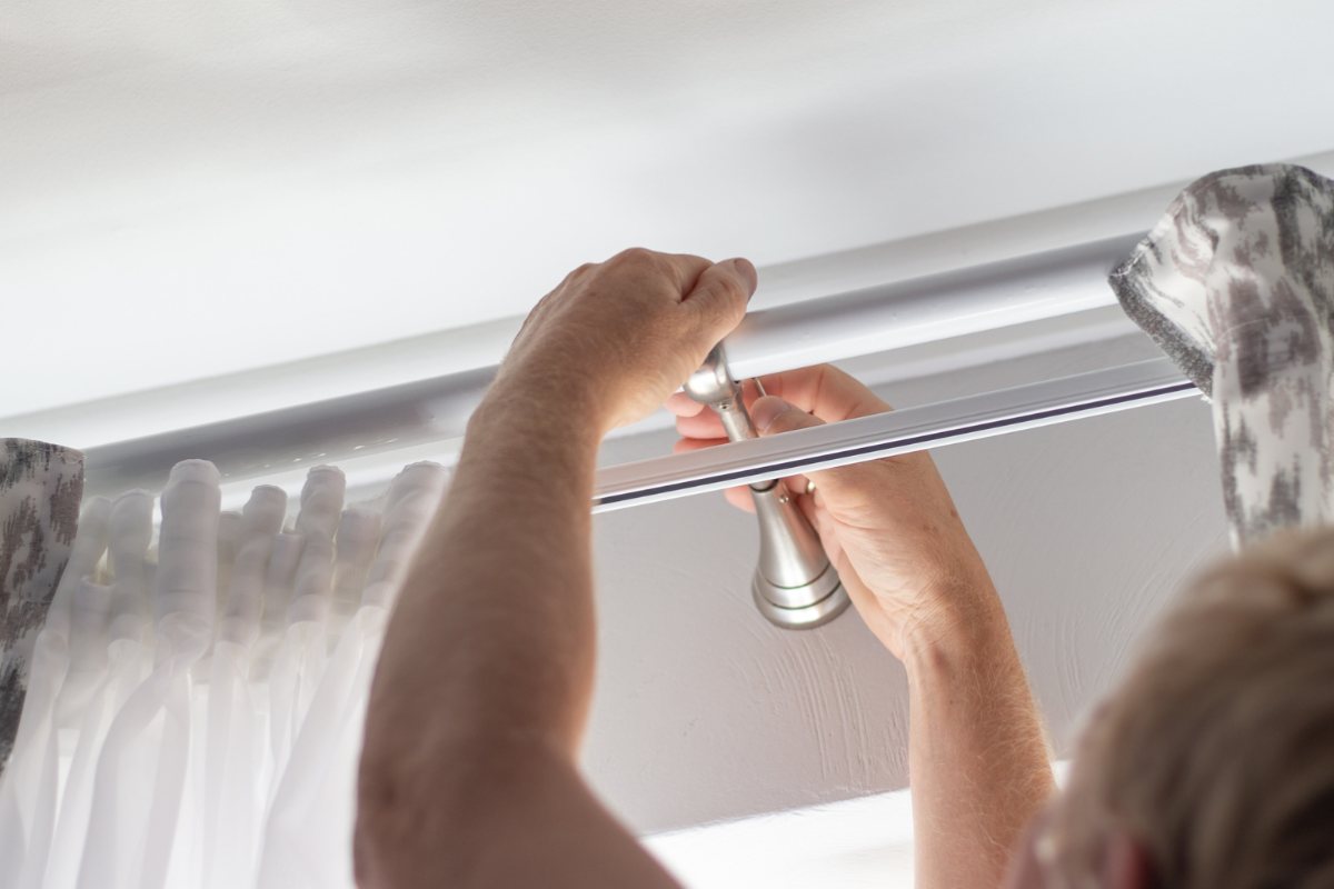 Uomo che smonta il bastone delle tende di casa